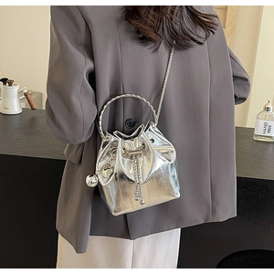 Detail of silver metallic bucket bag with round metal handle and drawstring closure