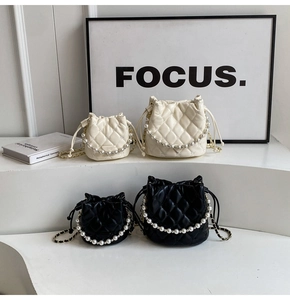 Détail de sacs seaux matelassés en noir et blanc avec chaînes élégantes en perles