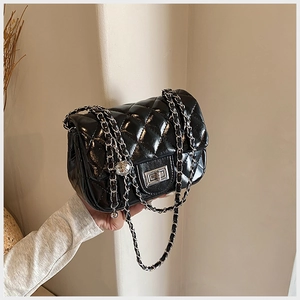 Close-up of black quilted shoulder bag with silver turn-lock and metal chain strap