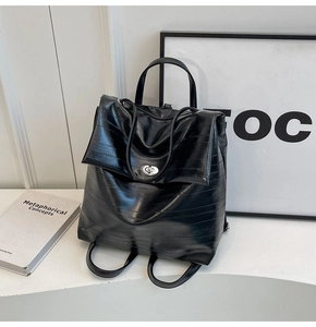 Macro detail of black pleated leather backpack featuring a silver twist lock closure