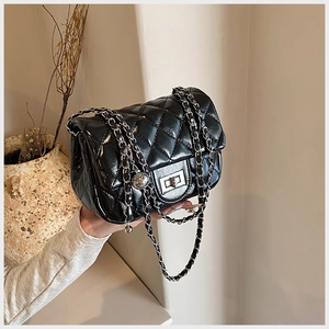 Close-up of quilted black leather bag with silver twist lock and metal chain strap