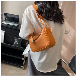 Vue arrière du mannequin portant un sac seau orange en cuir avec grain de litchi