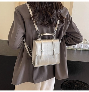 Detailed view of a silver metallic textured mini backpack with a flap and top handle