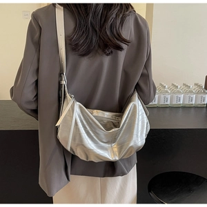 Silver metallic hobo bag with texture detail shown on model in a minimalist setting