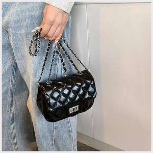Detail of quilted leather crossbody bag featuring silver chain strap and metal turn-lock