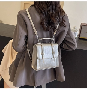 Detail of silver textured backpack with vertical embossing and circular metal buckles