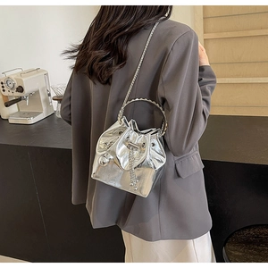 Detail of silver mirror bucket bag featuring metal chain strap and drawstring closure