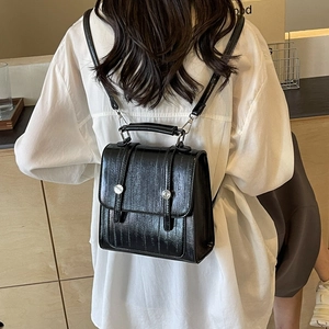 Retro black textured leather backpack with silver buckles shown on model's back