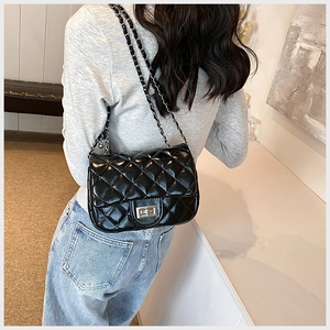Detail of black quilted leather shoulder bag with silver chain strap on model