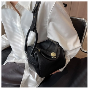 Détail du sac seau Lindy en cuir noir à motif litchi avec fermoir rotatif métallique