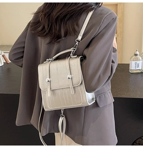 Silver metallic mini backpack featuring vertical texture and dual buckles on a model