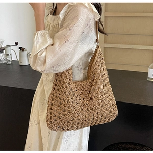 Close-up of bohemian hollow straw shoulder bag with woven texture and leather strap
