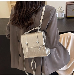 Detail of silver metallic textured backpack featuring vertical stripes and metal hardware