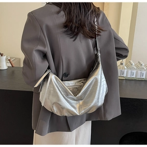 Detailed back view of a silver faux crocodile moon bag shown in a stylish cafe setting