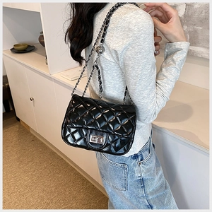 Close-up of black quilted leather shoulder bag with silver clasp and chain strap
