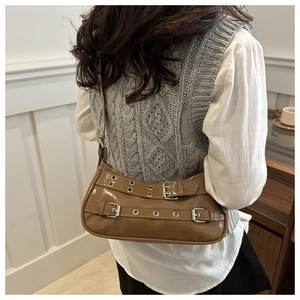 Close-up of brown patent leather underarm bag with silver buckles and eyelet straps