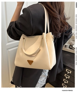 Chic beige tote bag with metallic logo styled on a classic black blazer outfit