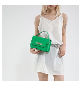 Fashionable bright green top handle flap bag with gold metal buckle on white dress model