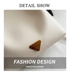 Detail of a vintage gold triangle metal plaque on a creamy white leather bucket bag