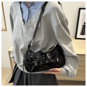 Detail of black patent leather hobo bag with punk silver buckles and metal eyelets