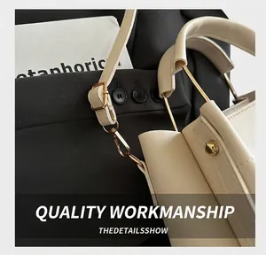 Detail view of cream PU leather handbag featuring metallic handles and golden hardware