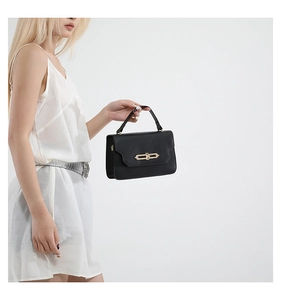 Close-up of elegant black handbag with gold twist lock and smooth faux leather texture