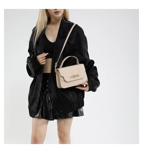 Detailed view of beige crossbody bag with premium leather texture and gold lock