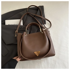 Detail of dark brown tote bag with metal triangle logo on a professional grey blazer