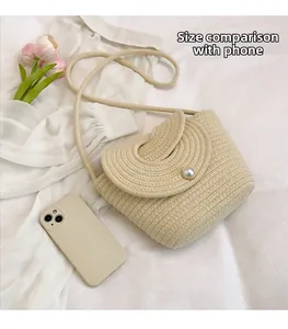 Dettaglio della borsa in paglia intrecciata crema con chiusura a perla e cellulare