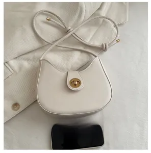 Detailed view of cream crescent bag with gold twist lock and size reference phone