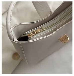 Close-up of a cream crescent bag showing a smooth gold zipper and refined leather texture