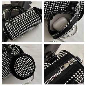 Detalle del bolso cilíndrico negro con tachuelas plateadas, cadena y mini monedero redondo