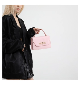 Pink flap handbag with gold double-ring buckle held by a model in a black suit