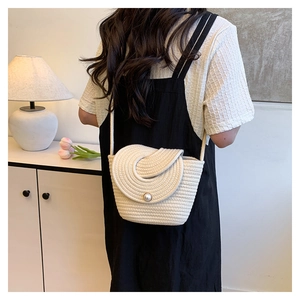 Detailed back view of a woman wearing a cream straw crossbody bag with pearl buckle