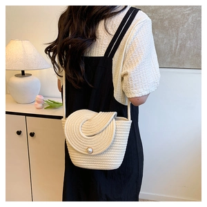 Détail du sac seau bohème tissé avec accent perle et textures ivoire élégantes