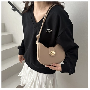 Détail du sac demi-lune beige avec fermoir doré et bandoulière à nœud sur le côté