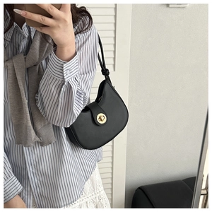 Détail du sac demi-lune noir avec fermoir doré et bandoulière à nœuds élégante