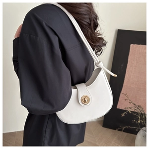 Détail du sac à bandoulière blanc en croissant avec fermoir doré rotatif et sangle nouée