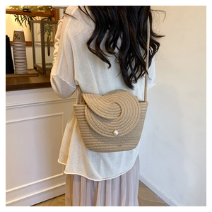 Détail du sac seau tissé avec rabat en spirale et perle centrale sur bandoulière