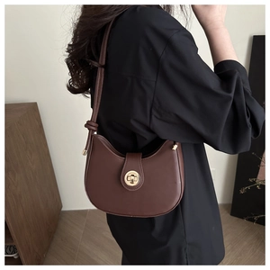 Brown hobo shoulder bag with golden round buckle and knot detail worn by a model
