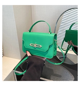 Detail of vibrant green leather handbag with gold metal clasp and sturdy top handle