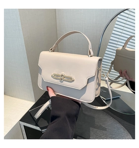 Detailed mirror reflection of a chic cream leather handbag with gold metal clasp