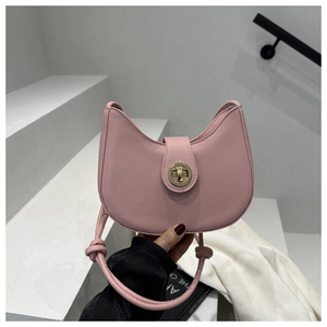 Vue détaillée du sac croissant rose avec fermoir rond doré et poignée à nœud décoratif