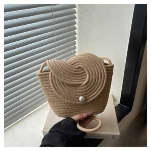 Detailed view of the woven texture and large pearl buckle on the beige mini beach bag