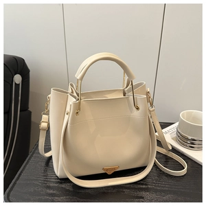 Detail of cream white bucket bag with round handles and gold triangular metal logo