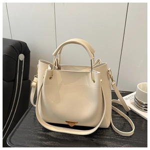 Detailed shot of cream bucket bag with metal handle on a magazine background