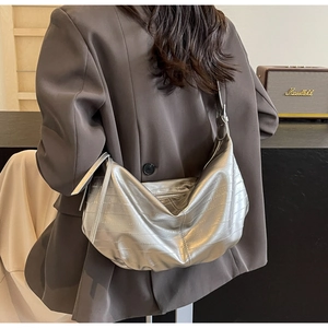 Close-up of silver crescent tote bag with crocodile texture on a model shoulder