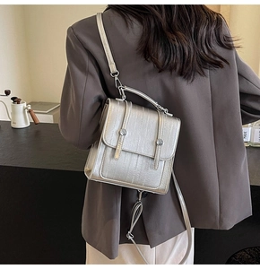 Rear view of a model wearing the metallic silver backpack in a modern cafe setting