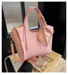Detailed view of pink lychee textured leather bucket bag with silk scarf handle