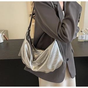 Side view of metallic silver crescent bag with crinkled faux leather texture and strap